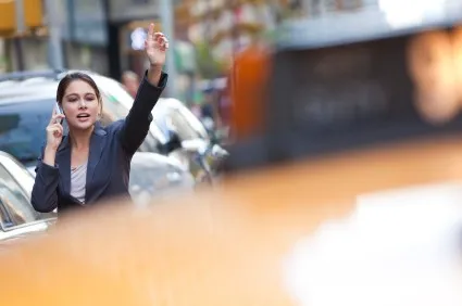 Young Woman on Cell Phone Hailing a Yellow Taxi Cab